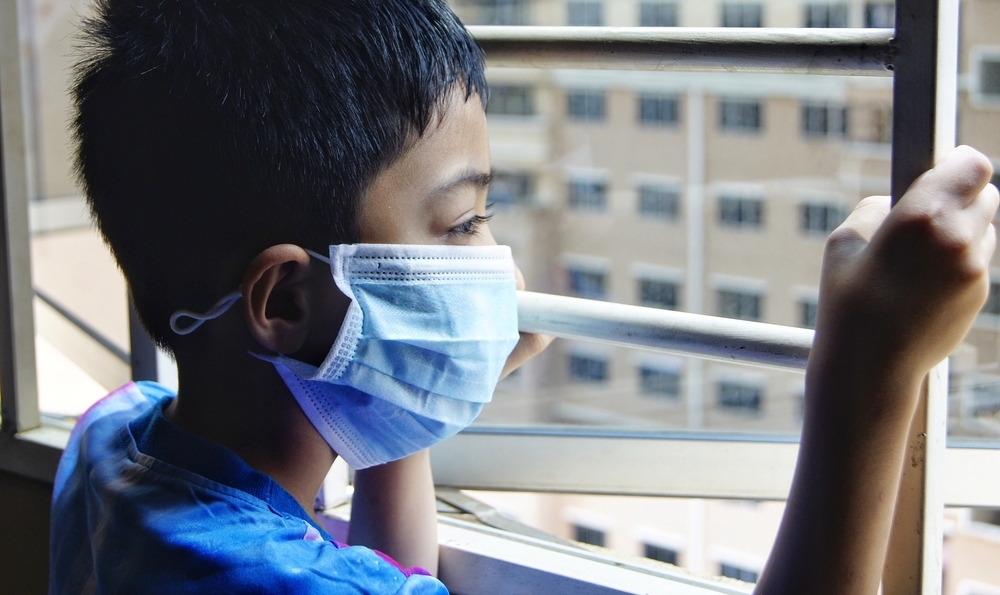 loosely masked boy looking out open window, holding onto ladder