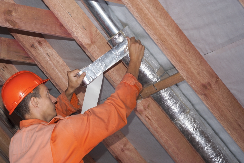 Man fixing duct in attic