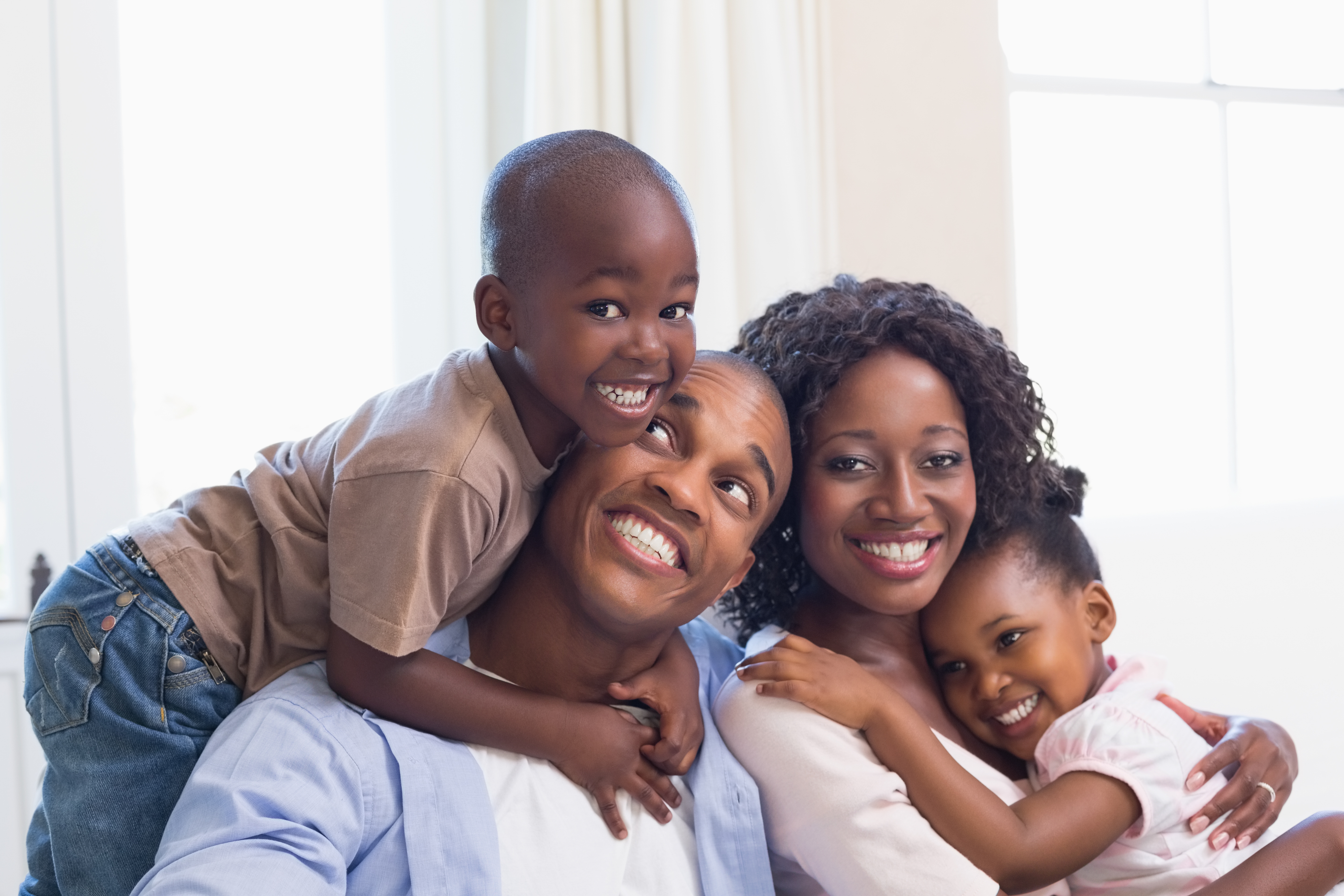 Happy Family Sitting Together With Little Boy and Girl Hugging Their Parents