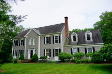 Large light gray home with white trim and manicured lawn