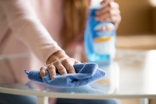 woman at home cleaning counter with rag and cleaning spray