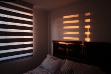 dark bedroom with sun rising through the shades