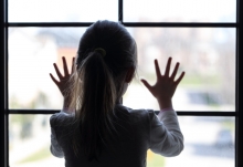 child against window of house