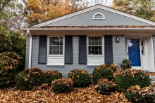 house in the fall with leaves on the bushes out front