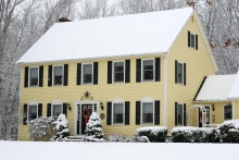 yellow two story classic colonial home during winter, christmas wreath front door