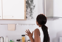 Woman looking at mold on wall