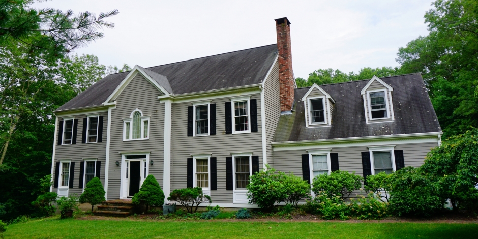 Large light gray home with white trim and manicured lawn