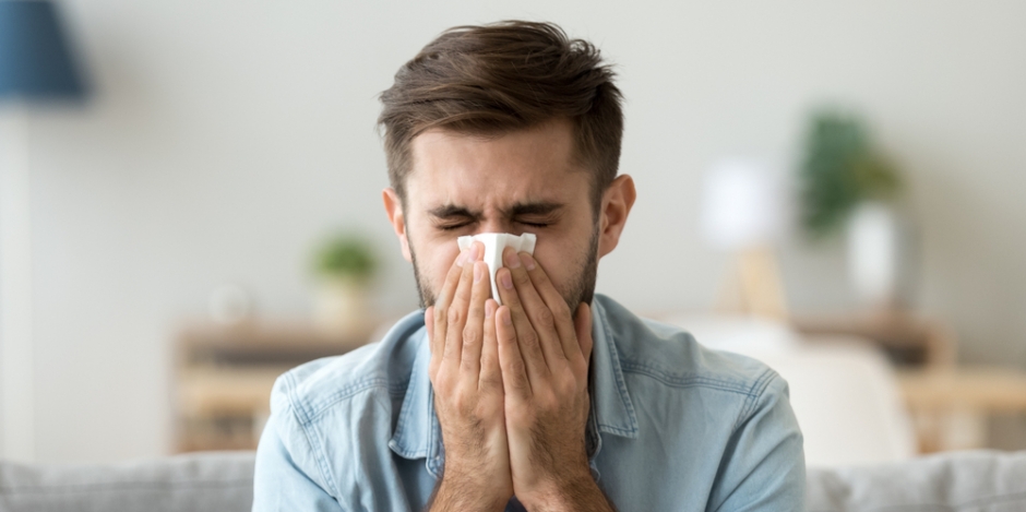man at home sneezing into tissue