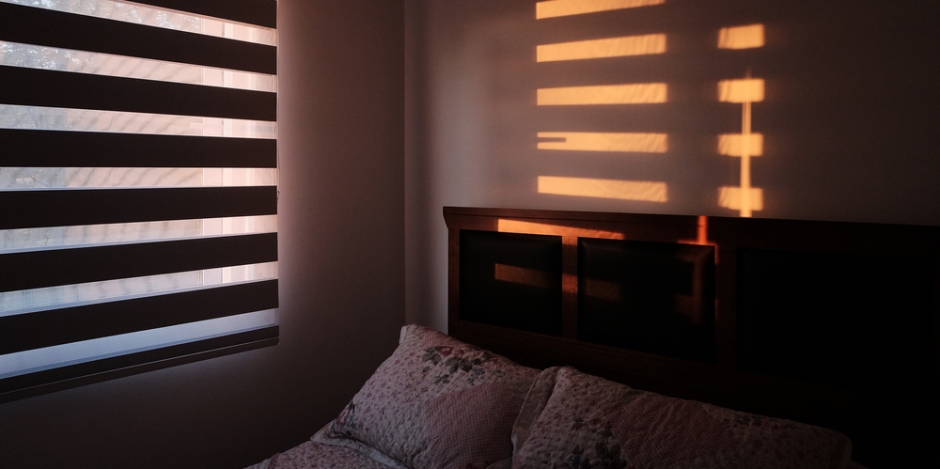 dark bedroom with sun rising through the shades