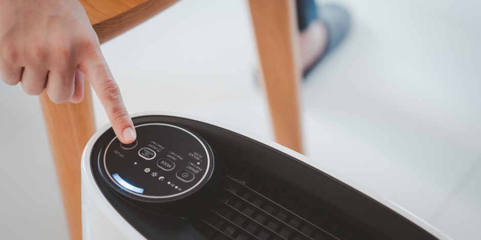 person turning on air purifier in home close up