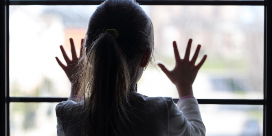 child against window of house