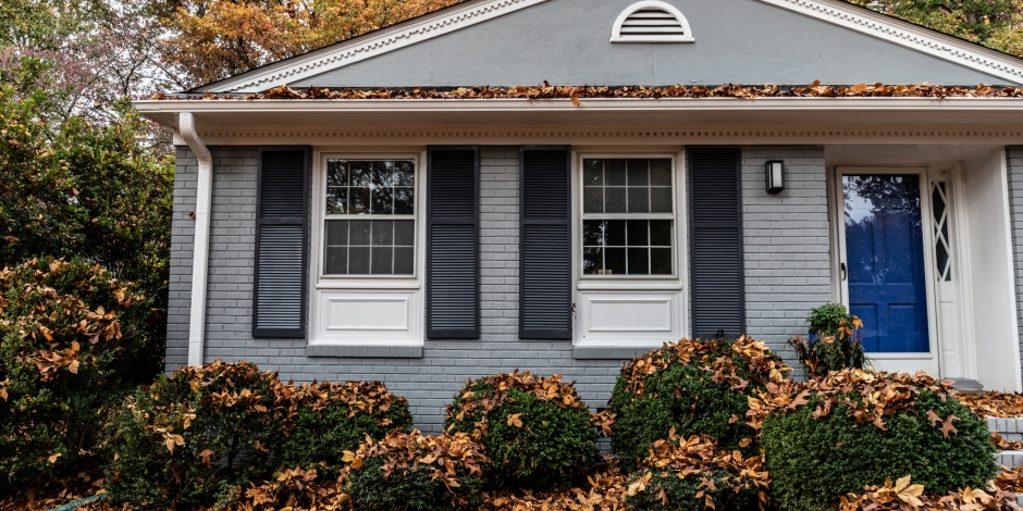 house in the fall with leaves on the bushes out front
