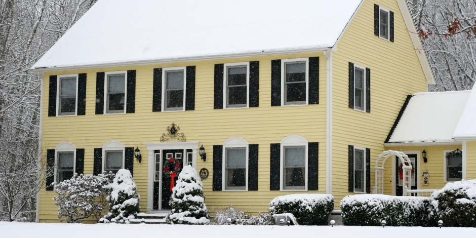 yellow two story classic colonial home during winter, christmas wreath front door