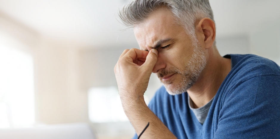 man pinching nose in headache at home