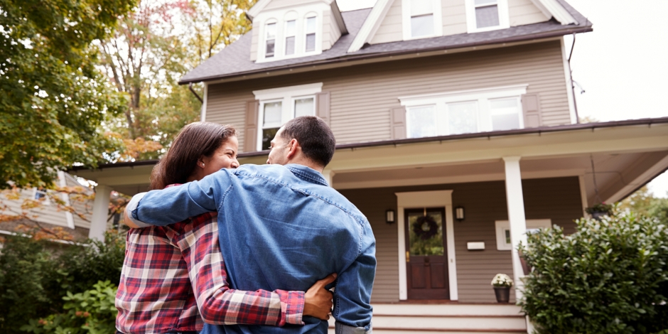 happy couple standing in front of home