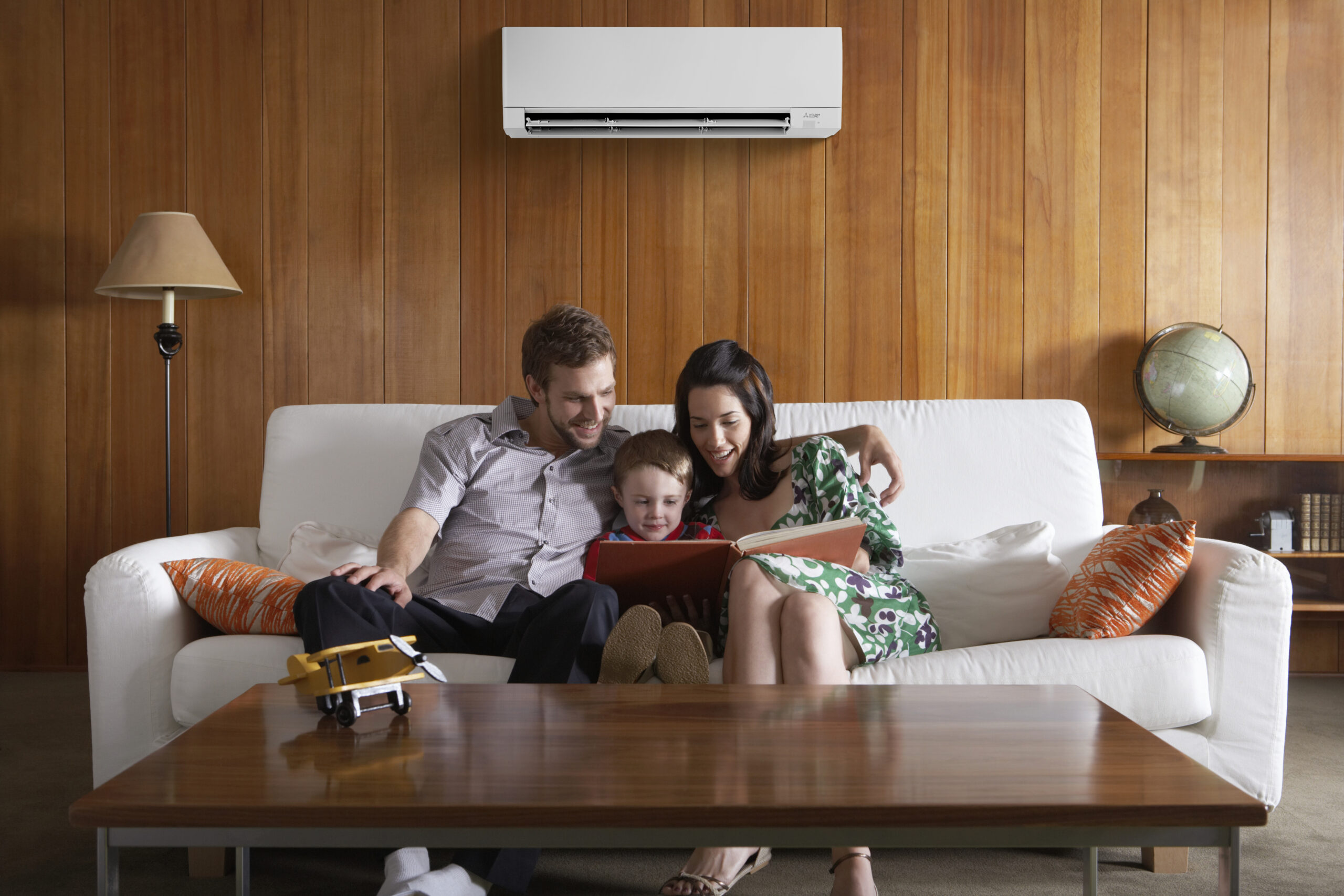 Happy family on couch under a Mitsubishi Heat Pump Mini-Split System